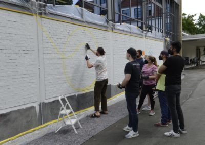 Schüler besprühen eine Wand mit Graffiti