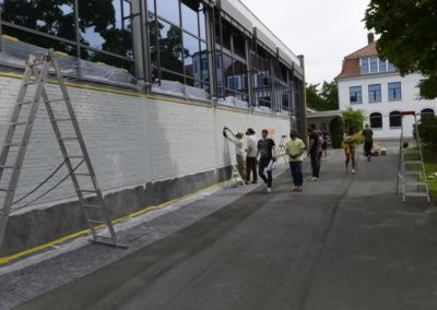 Schüler besprühen eine Wand mit Graffiti