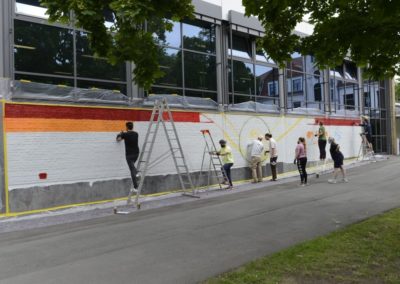 Schüler besprühen eine Wand mit Graffiti