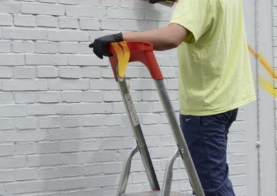 Schüler besprühen eine Wand mit Graffiti