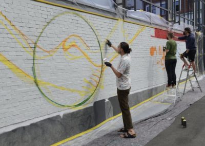 Schüler besprühen eine Wand mit Graffiti