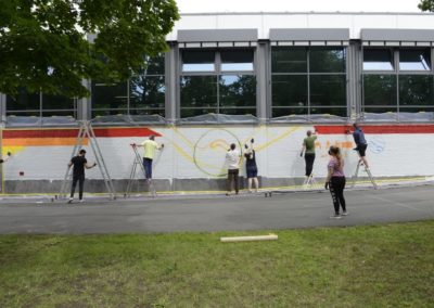 Schüler besprühen eine Wand mit Graffiti