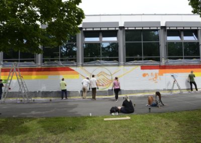 Schüler besprühen eine Wand mit Graffiti