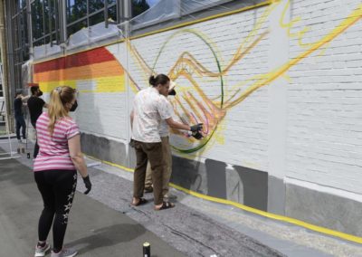 Schüler besprühen eine Wand mit Graffiti