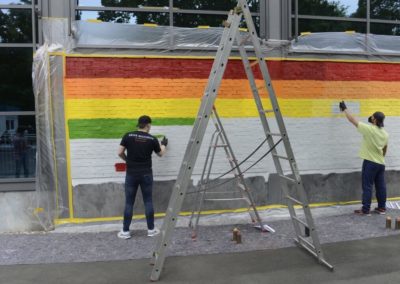 Schüler besprühen eine Wand mit Graffiti